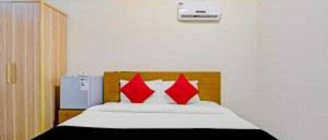 A hotel room with a bed, a wardrobe, and an air conditioning unit on the wall.