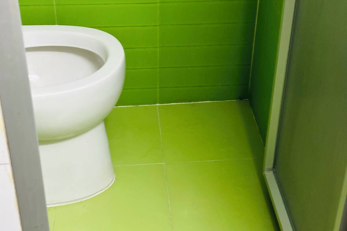Un baño pequeño con un inodoro blanco y azulejos verdes.