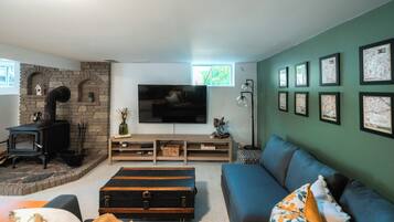 Una sala de estar con chimenea, un sofá, un televisor y cuadros en la pared.