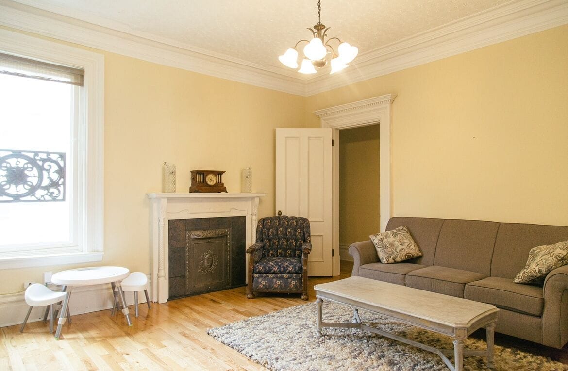 A living room with a fireplace, a sofa, a coffee table, and a patterned armchair.