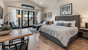 Une chambre spacieuse avec un grand lit, un coin repas avec une table et des chaises, et une vue sur l’extérieur grâce à une porte coulissante.