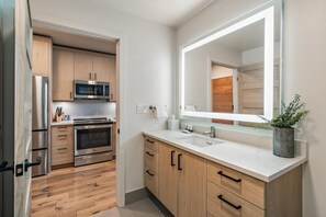 Une cuisine moderne avec des meubles en bois, des appareils en acier inoxydable, un grand miroir et une plante en pot.