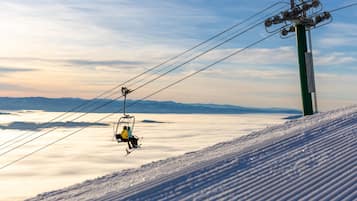 A ski lift with passengers, a snowy mountain slope, and a clear sky.