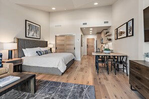Une chambre moderne avec un grand lit, des tables de chevet, un bureau et un coin repas.