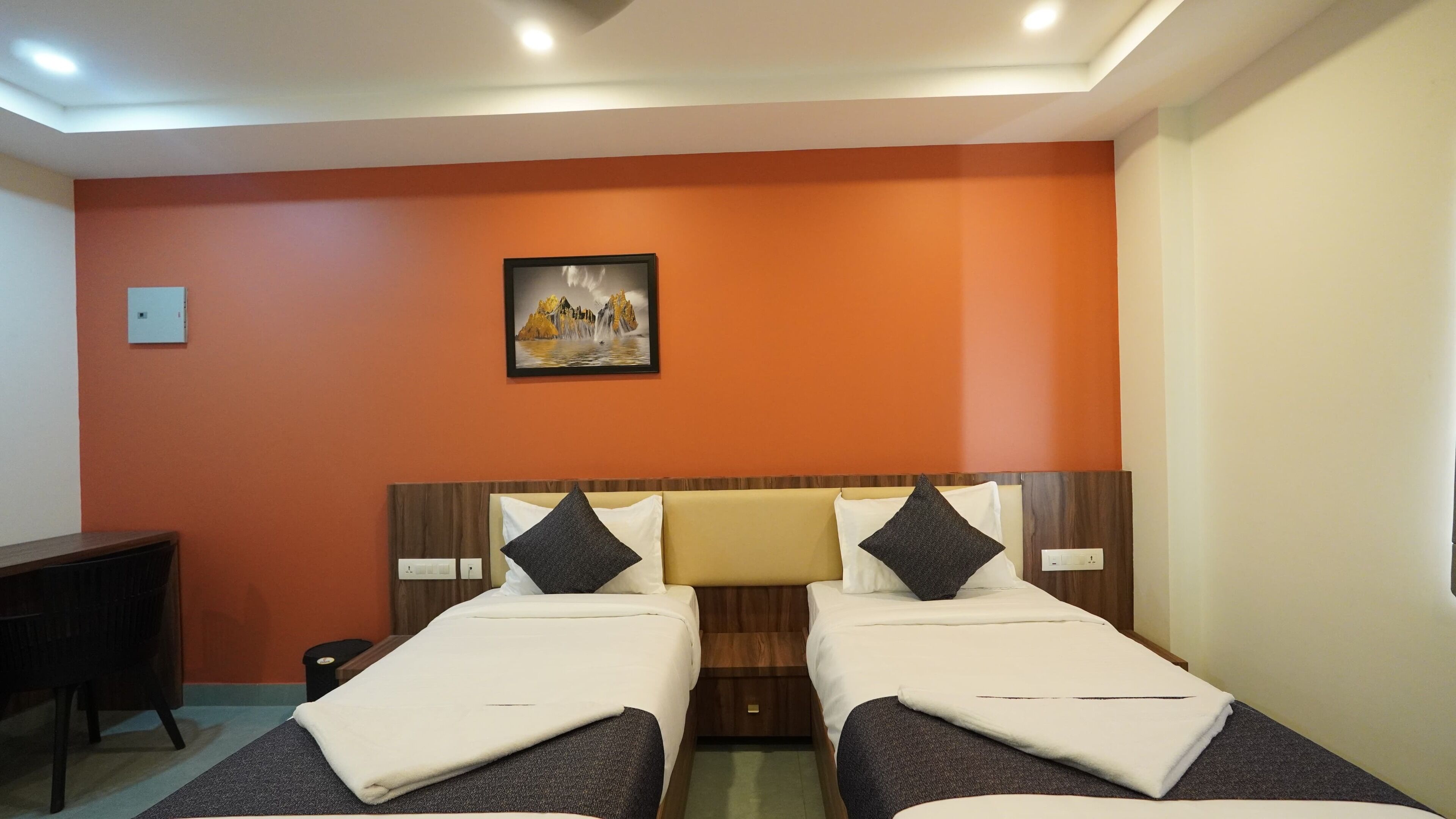 Habitación de hotel con dos camas individuales, un escritorio y un cuadro en la pared.