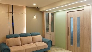 A modern living room with a beige sofa, a wooden wardrobe, and a tiled floor. - Hotel Hive Inn (Kozhikode)