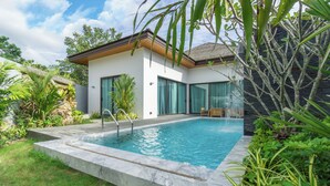 Una casa moderna con piscina, ventanas amplias y un jardín cuidado.