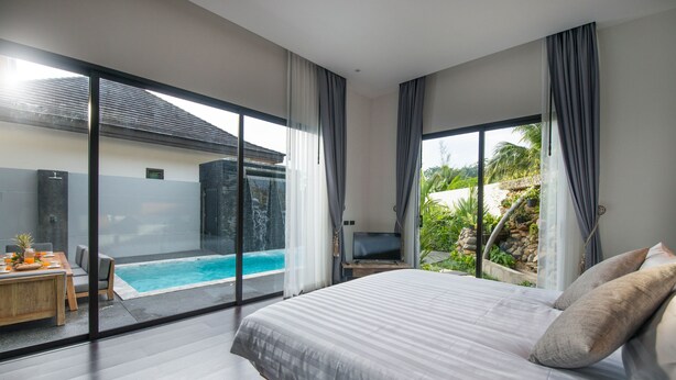 Un dormitorio con una cama grande, televisión y vista a una piscina.