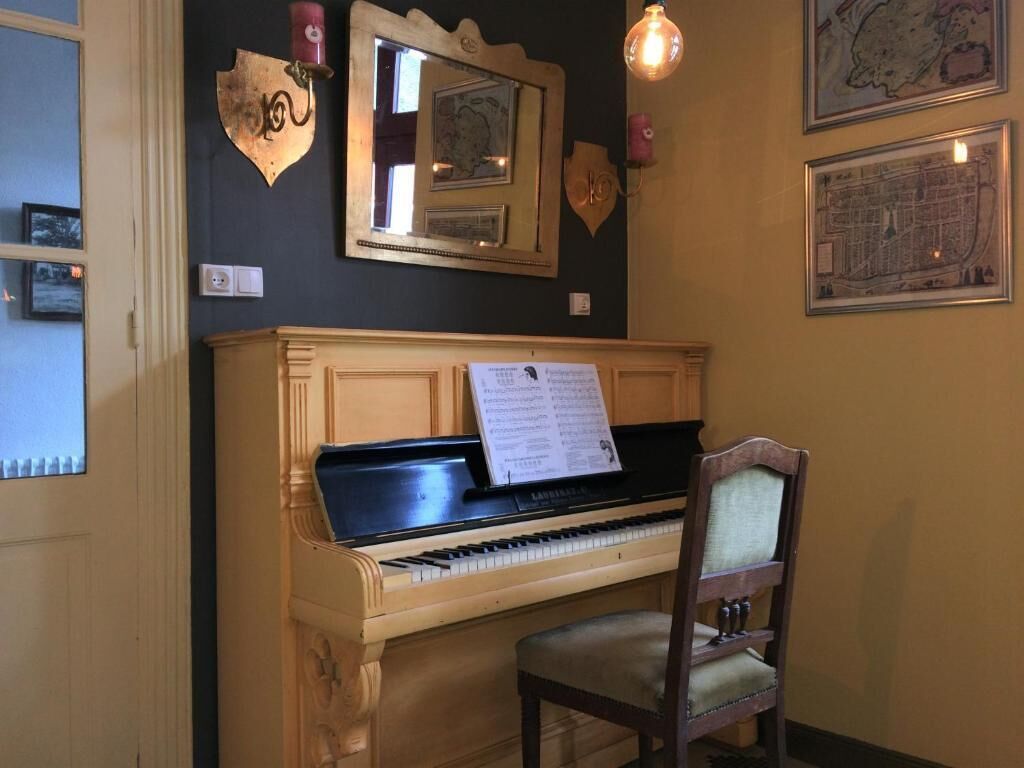 Un piano con partituras, una silla y decoración en la pared.
