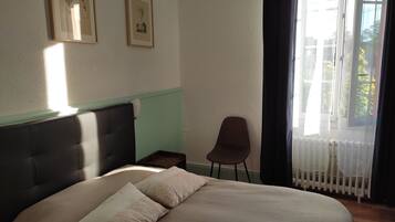 Un dormitorio con una cama, una silla y dos cuadros en la pared.