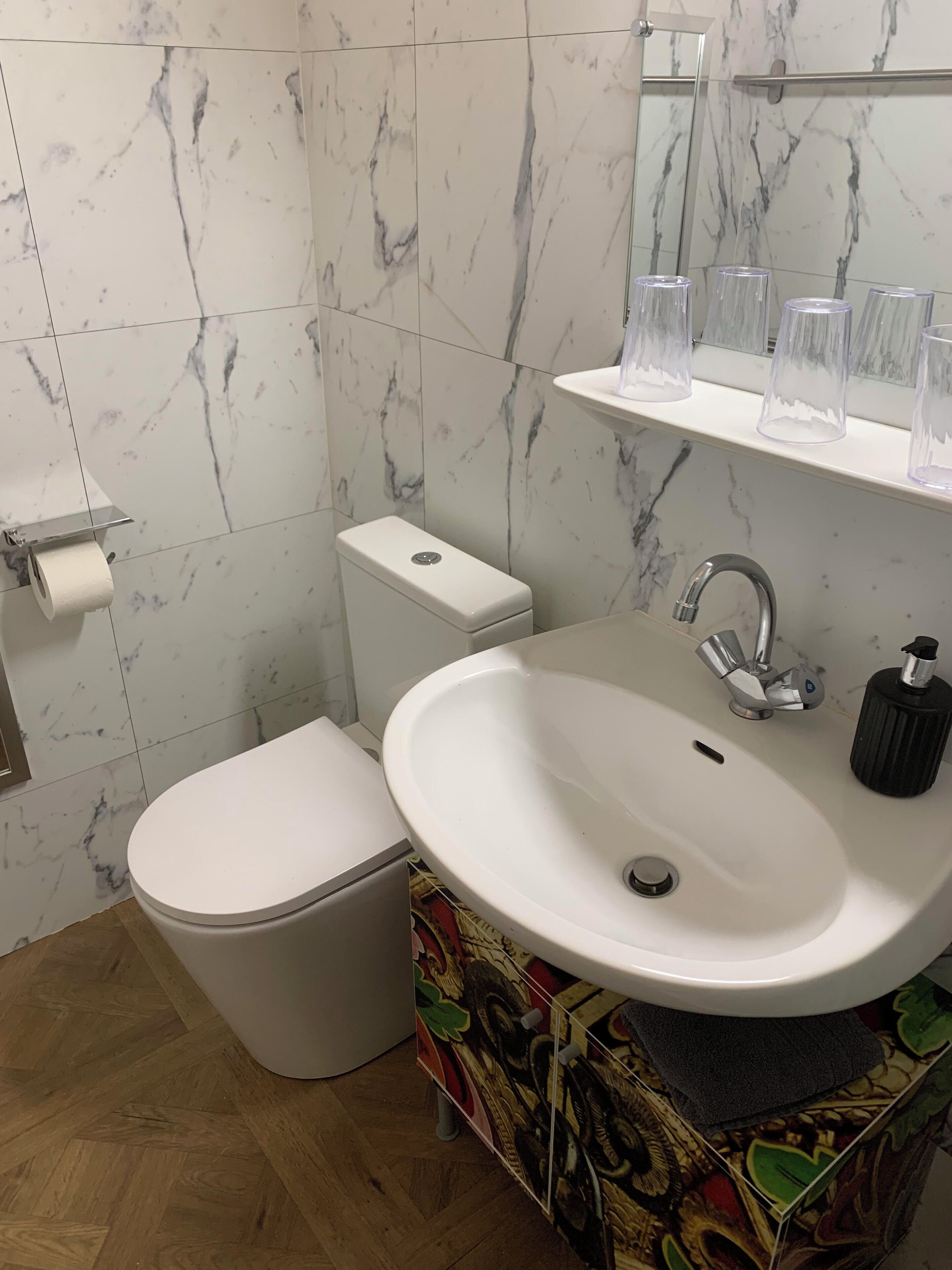 Un baño con inodoro, lavamanos y paredes cubiertas de mármol.