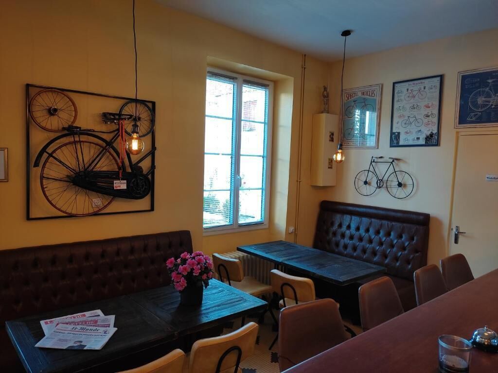 Un comedor con un cuadro mural grande con temática de bicicleta, una ventana con persianas, una mesa de madera oscura y un banco.