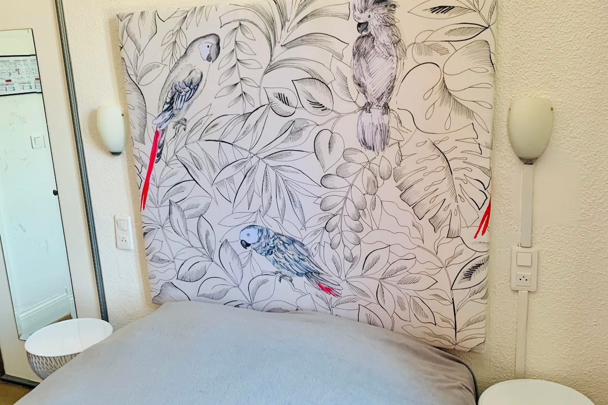 Een slaapkamer met een bed, een wandlamp en een hoofdbord met een patroon.