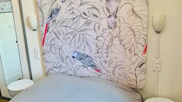 A bedroom with a bed, a wall-mounted lamp, and a patterned headboard.