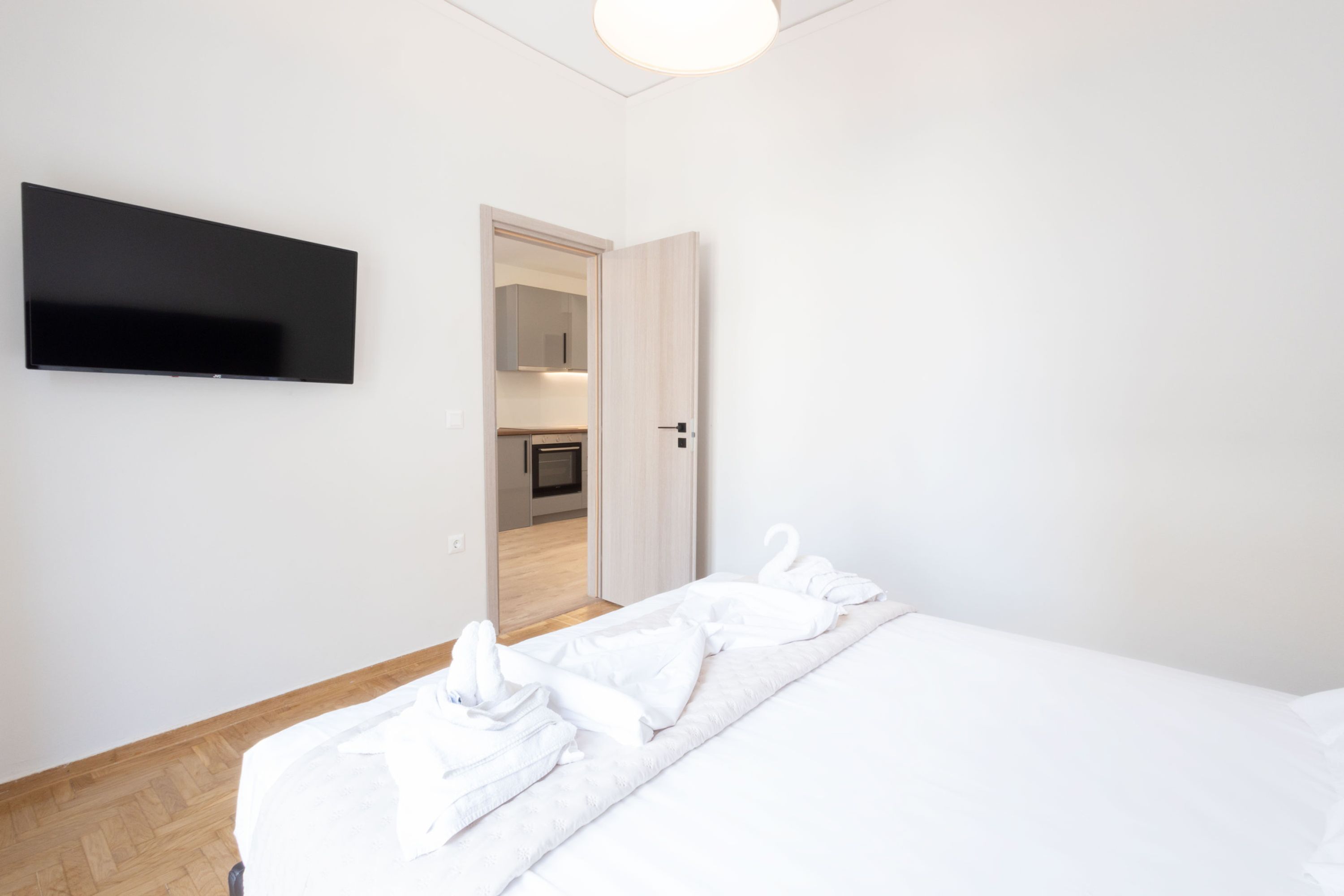 Een hotelkamer met een bed, een flatscreen televisie aan de muur en een houten vloer.