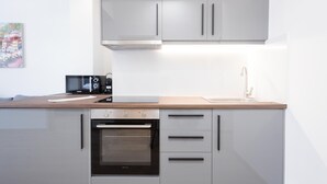 A modern kitchen with white cabinets, a built-in oven, a microwave, and a wooden countertop. - Modern 2-bedroom Gem Close to Metro (Athens)