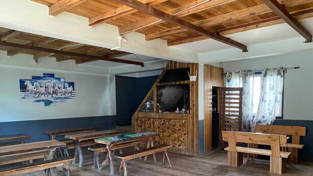 Un aula con bancos y mesas de madera, un escenario de madera y una pared azul con una pintura de un caballo.
