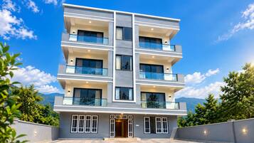 A multi-story building with balconies, large windows, and a clear sky.