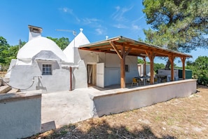 Ein modernes Haus mit überdachter Terrasse, kleiner Küche und Essbereich.