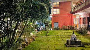 A courtyard with a brick building, potted plants, and a stone pathway. - Hotel Vibe (Pokhara)