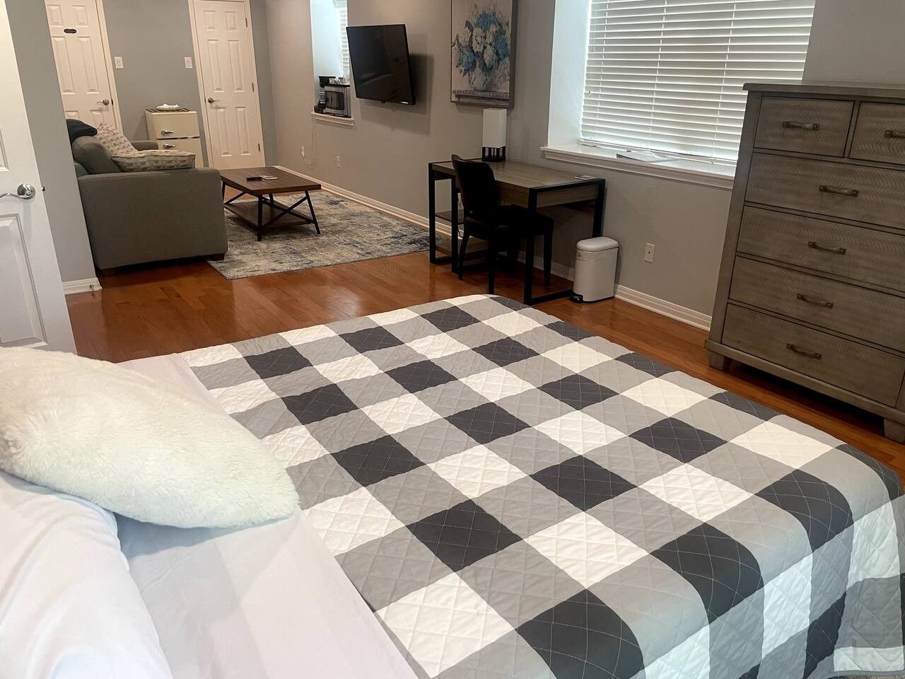 A bedroom with a bed, a desk, a chair, a dresser, and a television.