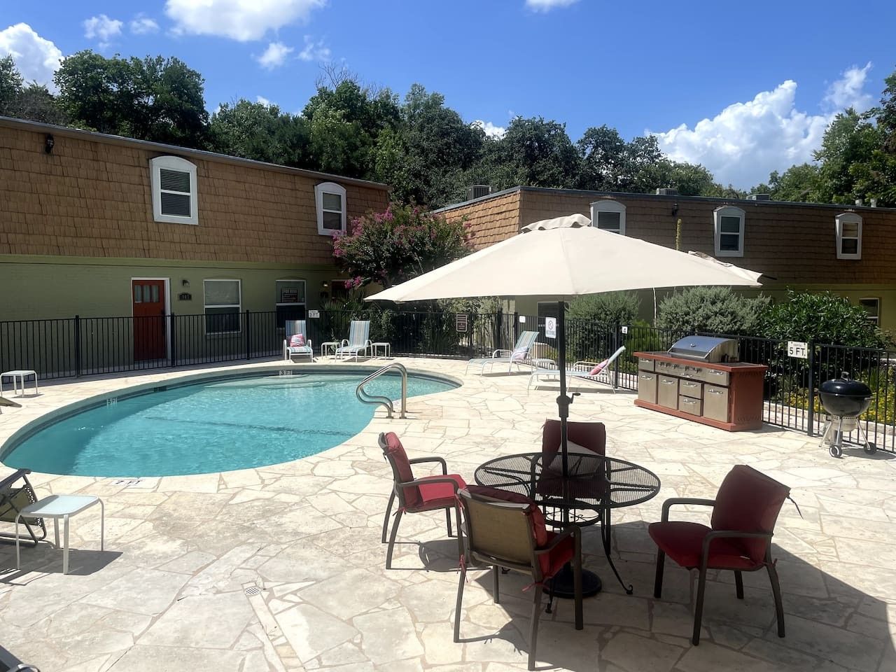 A swimming pool with lounge chairs and a barbecue area.