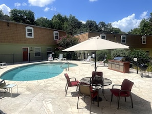 A swimming pool with lounge chairs and a barbecue area.