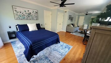 A bedroom with a bed, a ceiling fan, a desk, and a chair.