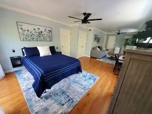 A bedroom with a bed, a ceiling fan, a desk, and a chair.