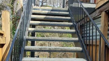 A wooden staircase with metal railings leading to a house.
