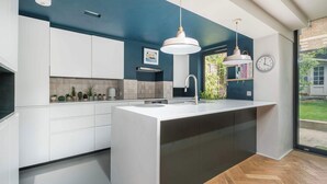 A modern kitchen with white cabinets, a large island, pendant lights, and a view of the outdoors.