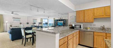 A modern kitchen with granite countertops, wooden cabinets, and a dishwasher.