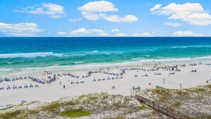 A beach with a clear sky, waves, and people.