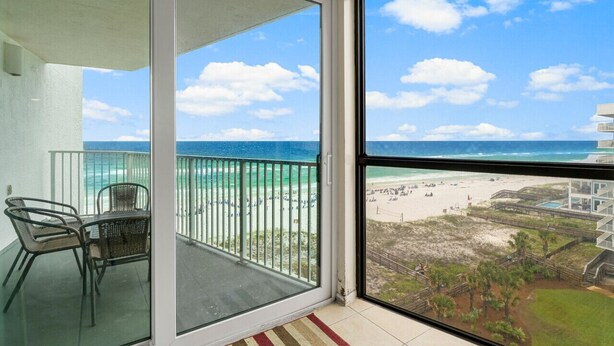 A balcony with a glass door, a table, and two chairs.