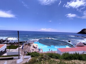 En pool vid kusten med utsikt över havet och en klippig strand.