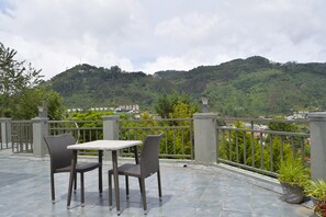 Une terrasse avec une table et des chaises, offrant une vue sur un paysage montagneux.