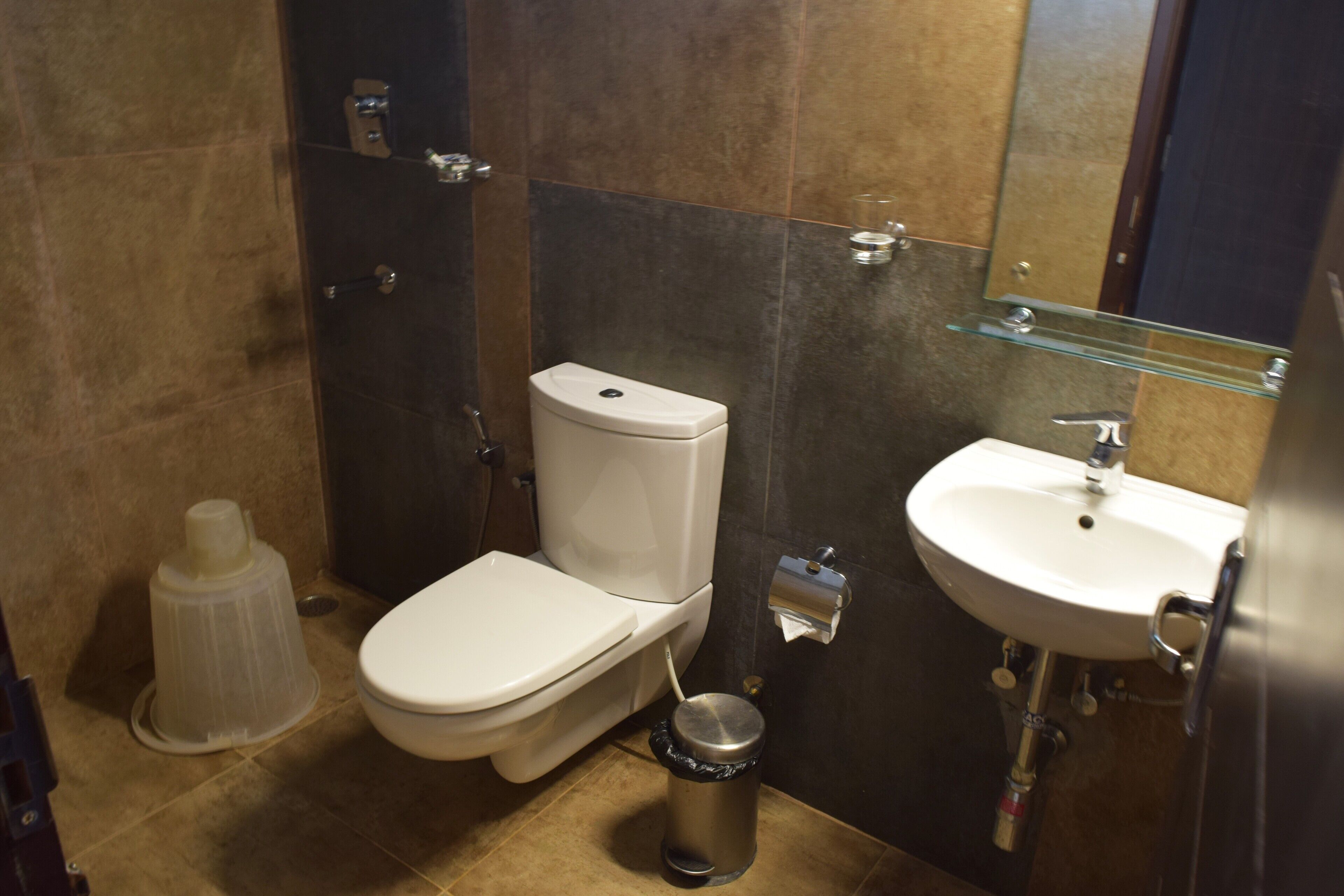 Un baño moderno con inodoro, lavamanos y un cubo de basura.