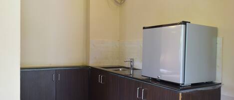 A compact kitchen with dark wooden cabinets, a stainless steel sink, and a built-in refrigerator.
