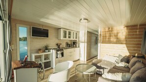 Een ruimtelijk ingerichte leefruimte met kitchenette, een eethoek en een zithoek met uitzicht op de omgeving.