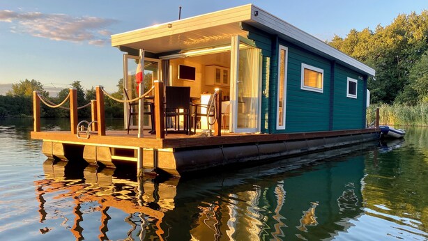 Een woonboot met een dek, een overdekt terras en een raam.