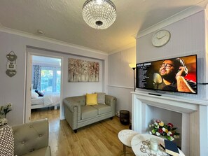 A living room with a television, a fireplace, a sofa, and a dining area. - Semi Detached House in Aldershot (Aldershot)