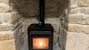 A wood-burning stove in a stone-walled room.