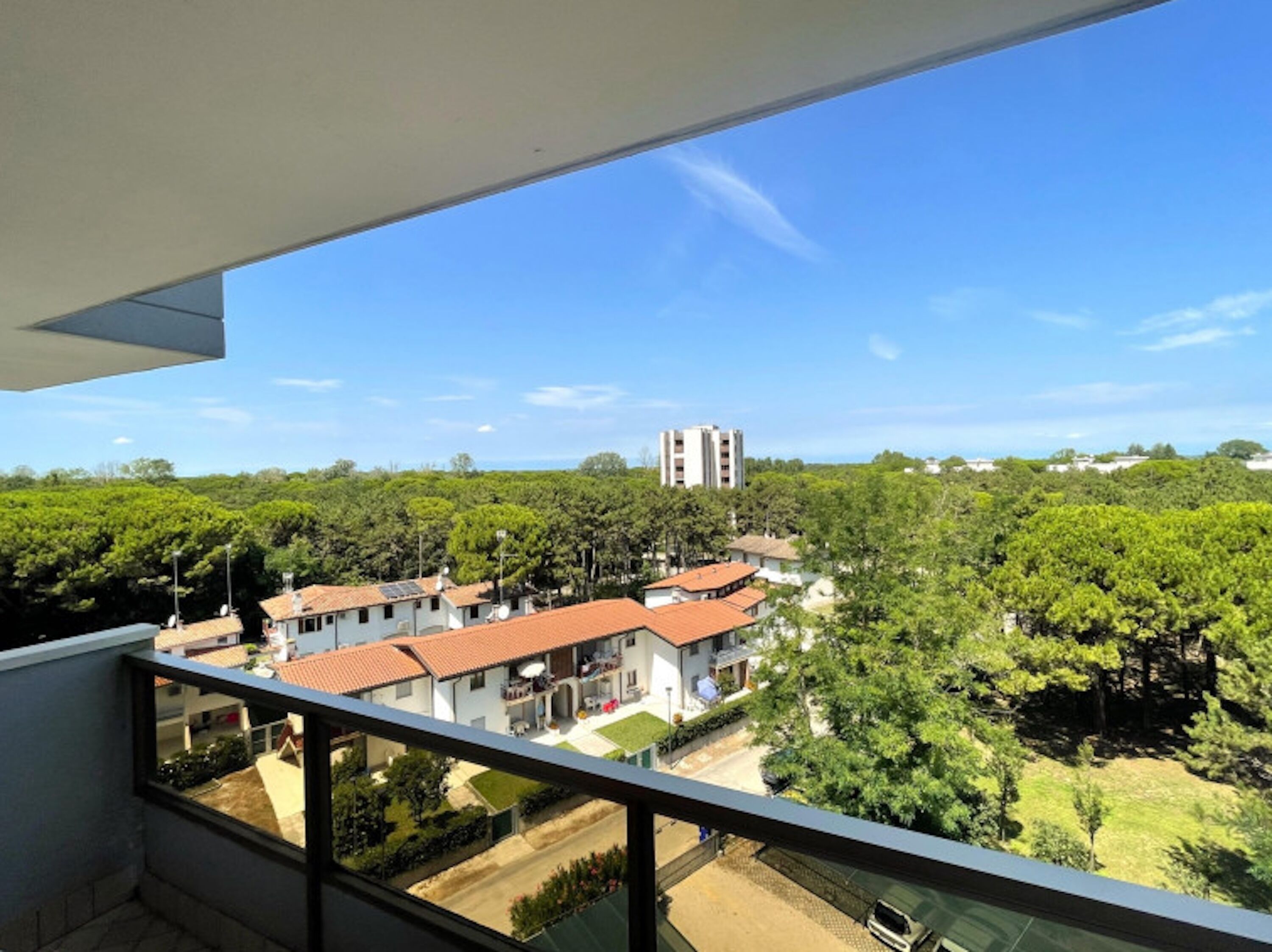 A balcony with a view of a residential area, including houses and a tall building in the distance.