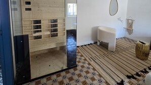 Una stanza con un divisorio in vetro, una panca, uno specchio e un pavimento decorato.