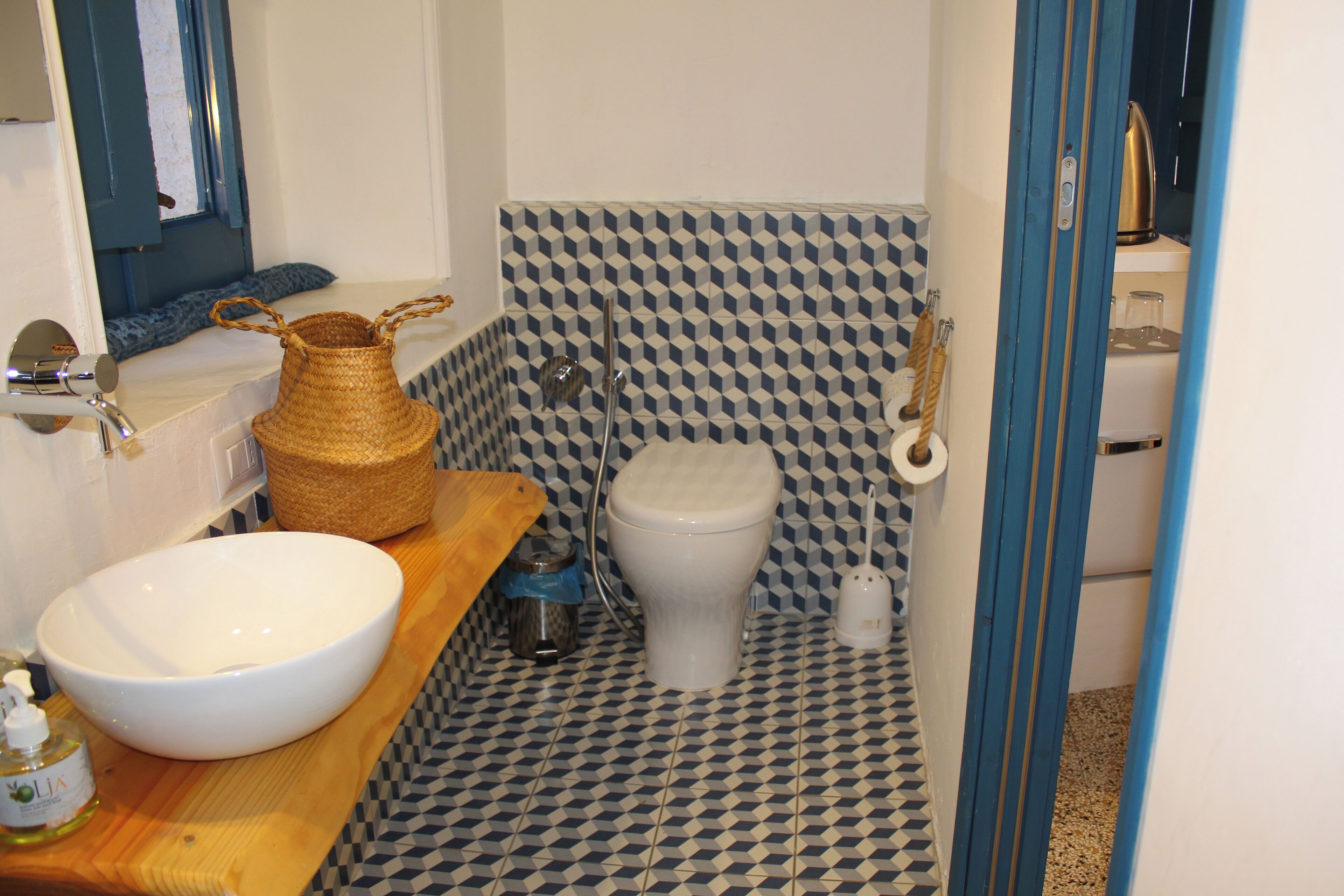A bathroom with a white sink, a toilet, and a patterned floor.