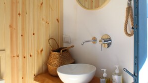 Un bagno con un mobile vanitario in legno, uno specchio rotondo, un lavandino bianco e un portasciugamani.