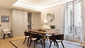 A dining area with a rectangular table, six chairs, a round mirror, and a window with a balcony. - A Splendide 3-BR/3BA close to Le Bon Marché (Paris)
