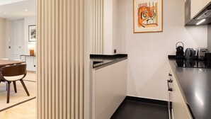 A modern kitchen with a black countertop, stainless steel appliances, and a framed artwork of a tiger. - A Splendide 3-BR/3BA close to Le Bon Marché (Paris)