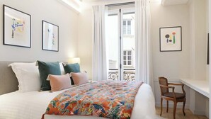 A bedroom with a bed, pillows, a chair, and artwork on the walls. - A Splendide 3-BR/3BA close to Le Bon Marché (Paris)