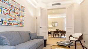 A modern living room with a grey sofa, a coffee table, and a colorful abstract painting on the wall. - A Splendide 3-BR/3BA close to Le Bon Marché (Paris)